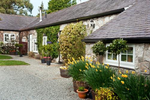a stone house with flowers in front of it at Tros Yr Afon Holiday Cottages and Manor House in Beaumaris