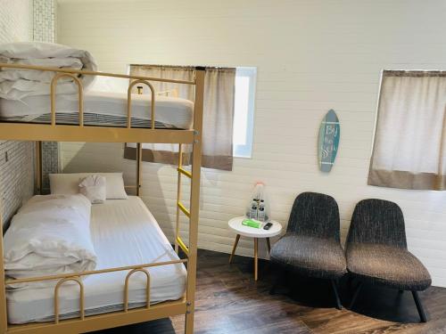 Pokój z łóżkiem piętrowym z 2 łóżkami piętrowymi i 2 krzesłami w obiekcie King Wow Inn w mieście Tainan