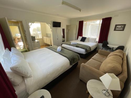 een hotelkamer met 2 bedden en een bank bij Happy Wanderer Motel Cohuna 70s style in Cohuna