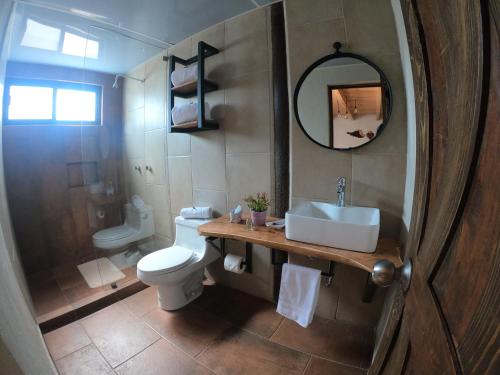 a bathroom with a sink and a toilet and a mirror at Hotel Viñedo los Arcángeles in Dolores Hidalgo