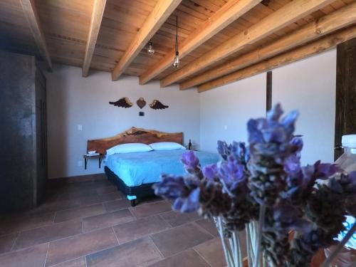 a bedroom with a bed and a vase of purple flowers at Hotel Viñedo los Arcángeles in Dolores Hidalgo