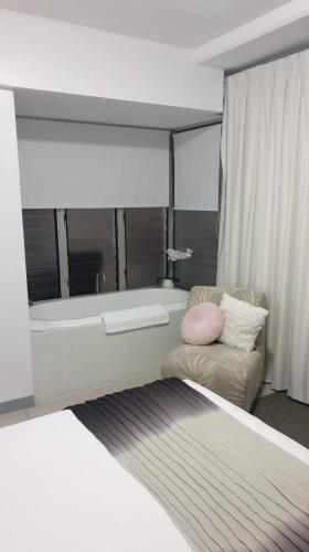 a bedroom with a bed and a tub and a couch at 1213/146 Sooning street, Nelly Bay, Magnetic Island. Qld 4819. One Bright Point. in Nelly Bay