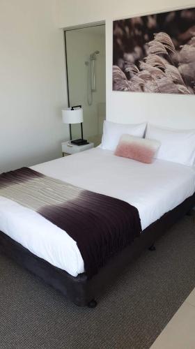 a bedroom with a large bed with a picture on the wall at 1213/146 Sooning street, Nelly Bay, Magnetic Island. Qld 4819. One Bright Point. in Nelly Bay