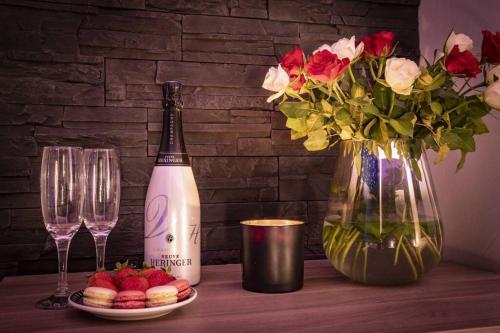 a table with a bottle of champagne and a vase with flowers at LE COTTAGE Zen LOVE in Foucherans