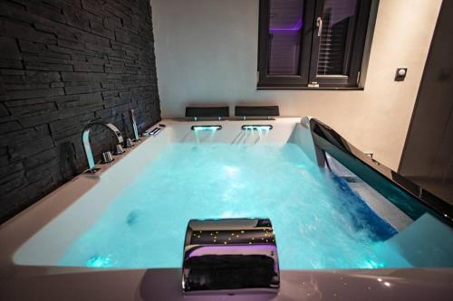 a hot tub with blue water in a room at LE COTTAGE Zen LOVE in Foucherans