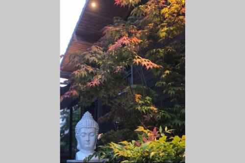 a statue in front of a building with a tree at LE COTTAGE Zen LOVE in Foucherans