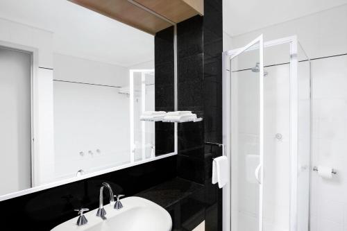 a bathroom with a sink and a glass shower at Mantra on Little Bourke Melbourne in Melbourne
