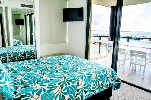 a bedroom with a bed and a view of the ocean at Absolute Waterfront - Tropical Aurora Top Floor Over The Water in Darwin