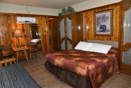 a bedroom with a bed in a room with wooden walls at The Kern Lodge in Kernville