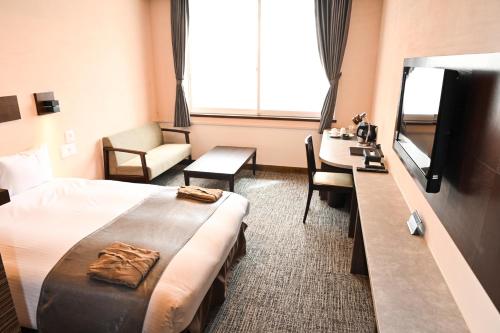 Habitación de hotel con cama, escritorio y TV. en Hotel Grand Vert Kyu Karuizawa, en Karuizawa