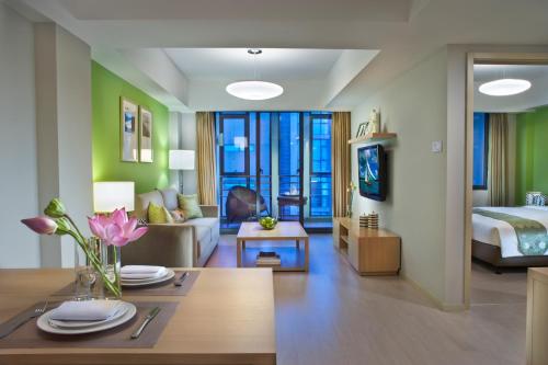 a living room with a couch and a bed at Citadines Zhuankou Wuhan in Wuhan