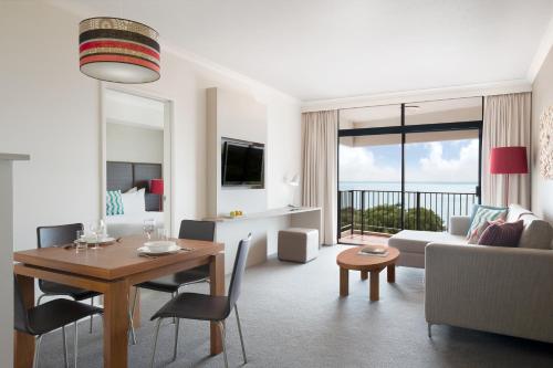a living room with a table and a living room with a couch at Mantra on The Esplanade in Darwin