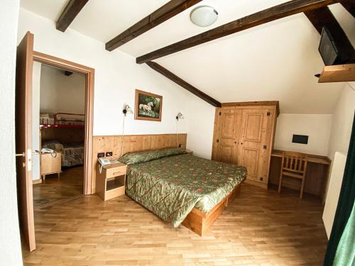 a bedroom with a bed and a table and a mirror at Garni Il Muretto in Lavarone