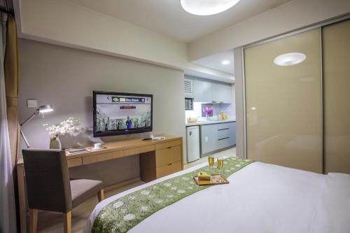 a bedroom with a bed and a desk and a television at Citadines Zhuankou Wuhan in Wuhan