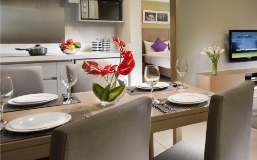 a dining room table with red flowers and wine glasses at Citadines Zhuankou Wuhan in Wuhan