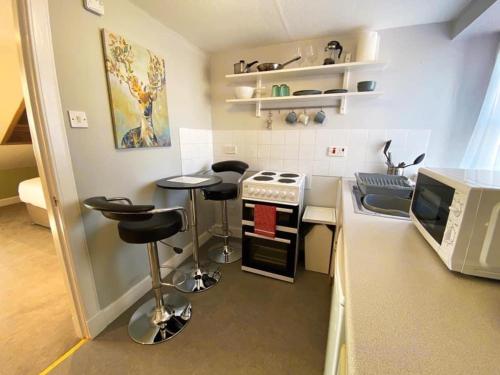 a kitchen with a stove and stools and a microwave at Studio Apartments on the Square in Kelso