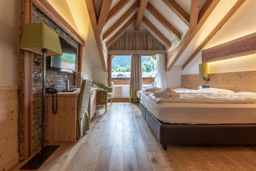 Alpholiday Dolomiti Wellness & Family Hotel في ديمارو: غرفة نوم بسريرين ونافذة كبيرة