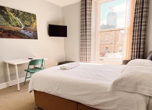 a bedroom with a bed and a desk and a window at Studio Apartments on the Square in Kelso