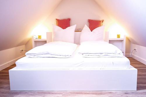 Cette chambre mansardée comprend 2 lits avec des oreillers blancs. dans l'établissement Flippi-s-Hues-WEST, à Westerland