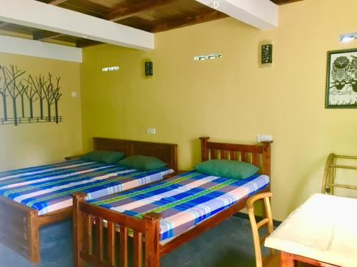 2 łóżka w pokoju z żółtymi ścianami w obiekcie Owl's Nest Chalet w mieście Udawalawe