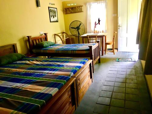 a bedroom with two beds and a dining room with a table at Owl's Nest Chalet in Udawalawe