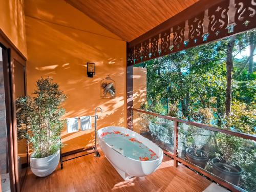 a bathroom with a tub and a window with plants at Loboc River Resort in Loboc