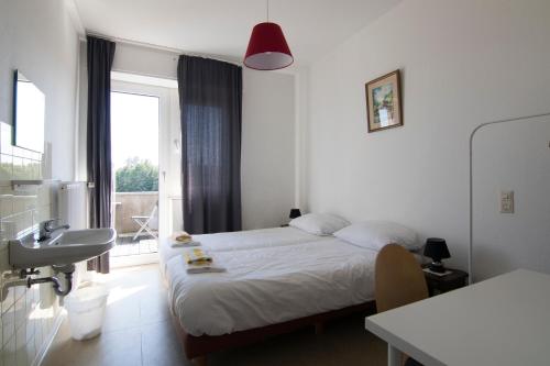 a bedroom with a bed and a sink and a window at World House Wetten in Kevelaer