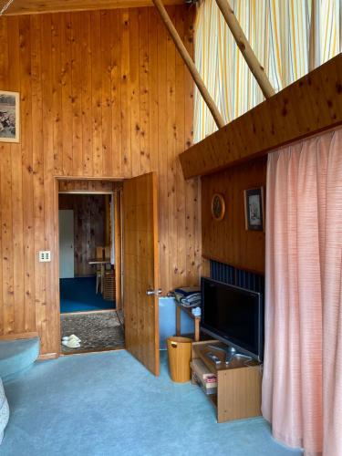 a living room with wood paneling and a television at 花緑里-Hanamidori-そしの山荘 岐阜下呂金山郡上貸切ロッジ高原リゾート in Gujo