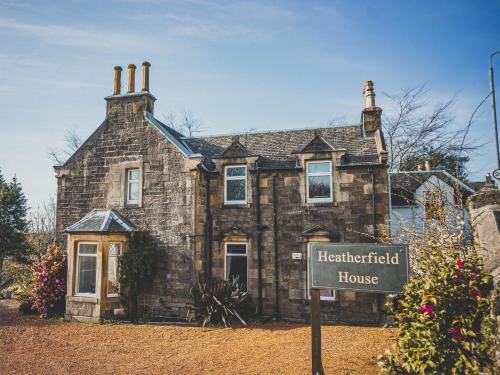 an old stone house with a sign in front of it at Heatherfield House in Oban