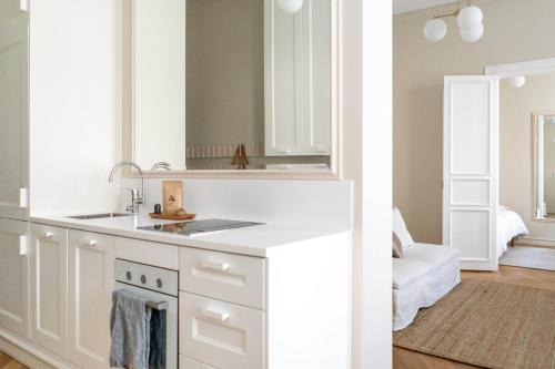 a white kitchen with a sink and a mirror at Roost Roobert 3 in Helsinki