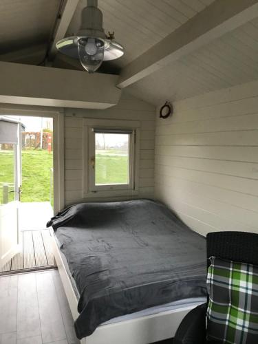 Bett in einem kleinen Zimmer mit Fenster in der Unterkunft Waterhut 2 Aduarderzijl in Feerwerd
