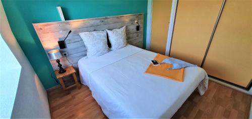 - une chambre avec un grand lit blanc et une tête de lit en bois dans l'établissement Appart'Hôtel du Bout du Monde, à Camaret-sur-Mer