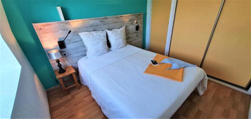 1 dormitorio con 1 cama blanca grande y cabecero de madera en Appart'Hôtel du Bout du Monde en Camaret-sur-Mer