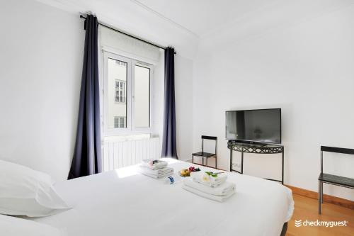- un lit blanc avec des serviettes et une télévision dans la chambre dans l'établissement Fancy apartment - 2BR-6P - Gare de l'Est, à Paris
