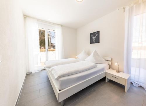 a white bedroom with a bed and a window at Braviscasa - Ferienresidenz Bärenhof Titisee in Titisee-Neustadt