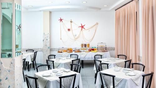a dining room with white tables and chairs at Albergo Gloria in Bellaria-Igea Marina