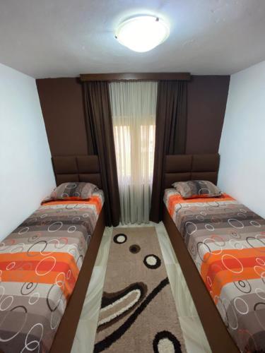 two beds in a small room with a window at Apartment Jovicevic in Rijeka Crnojevića