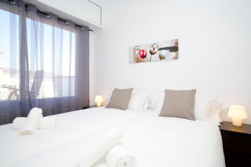 a white bedroom with a large white bed and a window at Attic Bcn Central Terrace in Barcelona