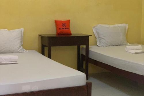 two beds in a room with a box on a table at KoolKost near Budi Mulia Siantar in Pematangsiantar