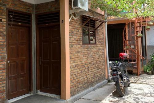 a motorcycle parked next to a brick building with two doors at KoolKost near Budi Mulia Siantar in Pematangsiantar