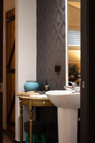 a bathroom with a sink and a mirror at Piccolo Cosy Cottage with views in Hepburn