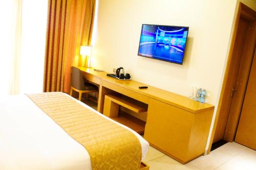 a hotel room with a desk with a television on the wall at K Hotels Entebbe in Entebbe