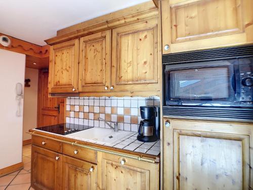 La cuisine est équipée de placards en bois, d'un évier et d'un four micro-ondes. dans l'établissement Les Alpages de Reberty, aux Menuires