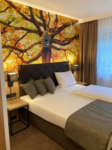 a bedroom with a large tree mural on the wall at Waldhotel Ehrental in Schmalkalden