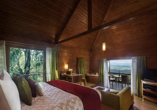 a bedroom with a large bed and a large window at The Tamara Coorg in Kakkabe