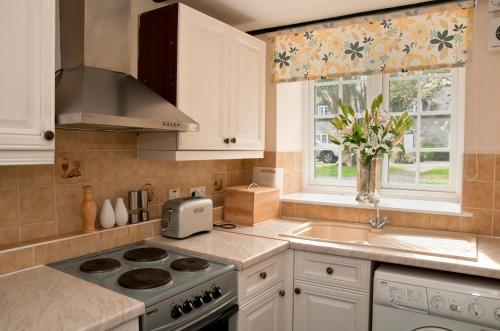 a kitchen with a stove and a sink and a window at Tros Yr Afon Holiday Cottages and Manor House in Beaumaris