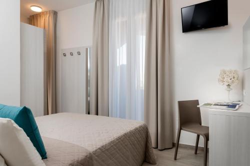 a bedroom with a bed and a desk and a television at Hotel Raffaello in Bellaria-Igea Marina