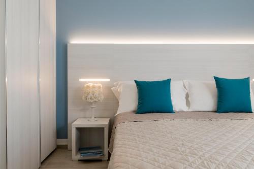 a bed with blue pillows and a lamp on a table at Hotel Raffaello in Bellaria-Igea Marina
