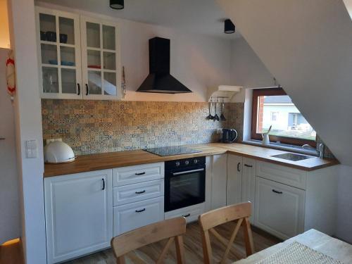 a kitchen with white cabinets and a sink and a stove at Morskie Opowieści in Żarnowska