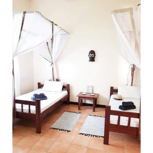 a room with two beds and two tables at Hakuna Matata Villa in Paje